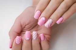 The hand of a young woman. The nails are covered with pink gel polish for Valentine's Day. Nail art and design ideas, heart.
