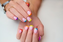 Hands of a young woman with a manicure. The nails are covered with gel polish with colored French.