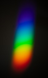 Rainbow color spectrum effect on wall, light scatter after hitting the glass object on to a dark wall.