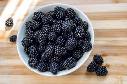 Blackberries in a white bowl on a wooden table