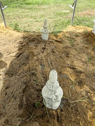 Tombstone sitting in the middle of a pile of soil