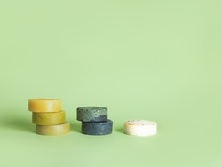 Six natural handmade round soaps in the form of the stairs opposite the green background, in the earth colors, zero waste bathing concept.