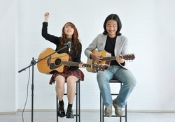 joyful duo artist playing guitar in music academy and a girl hand up for cheer up spectator concert