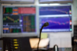 A microphone shot of a special phone system on trading floors.  In the background there is a blur image of monitors with trading graphs, charts and headlines.