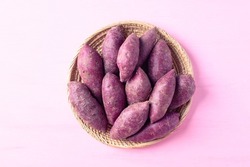 Purple sweet potatoes in basket on pink background, Top view