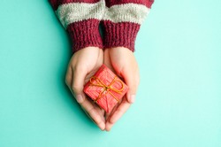 Woman holding red giftbox by hand on green background