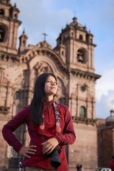 Tourist in the main square of cuzco, holding his camera, with a church in the background