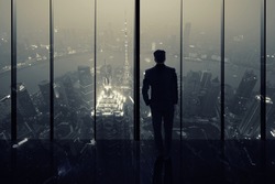 Silhouette of a Business Man looking out of high rise office window at night