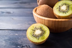 Kiwi fruit in a bowl on wooden background. Copy space