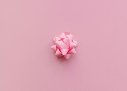 Decorative bow Close up photo in minimal style Pink paper gift bow on pink background Template for posters and banners