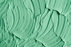 Green cosmetic clay (facial mask, face cream, body wrap) texture close up, selective focus. Abstract background with brush strokes.