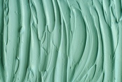 Green cosmetic clay (kelp facial mask, face cream, spirulina body wrap) texture close up, selective focus. Abstract background with brush strokes. 