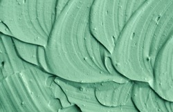 Green cosmetic clay texture close up. Abstract background with brush strokes.