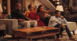 Portrait of Happy Indian Family Enjoying Movie Playing on TV at Home Together. Parents and Young Adult Children Share Love for Cinema, watching Favourite Streaming Service TV Shows.