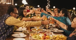 Happy Indian Family Having a Feast and Celebrating Diwali Together: Group of People of Different Ages in Their Traditional Clothes Raising Glasses and Making a Toast in a Backyard Garden