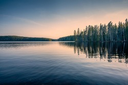 Forest lake in Sweden on a spring late afternoon, after sunset. Bredsjön lake in Stjärnfors under a blue-pink soothing sky. Relaxing nature image. Explore Scandinavia. 