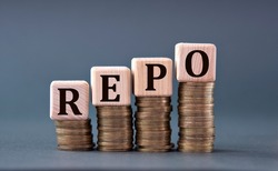 REPO (Repurchase Agreement) - word on wooden cubes on coins on a gray background. Business concept