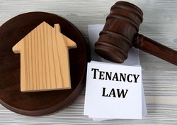 TENANCY LAW - words on a white sheet against the background of a judge's hammer and a wooden house
