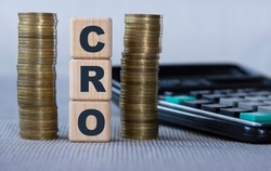 CRO (Chief Revenue Officer) - acronym on wooden cubes on the background of coins and calculator. Business and finance concept