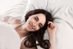 Young girl in the morning,lying in bed sleeping after hard work day tired.Nude makeup. Warm toning image.Fresh bedclothes,furnishing shop,new day, weekend,washing or laundry concept.