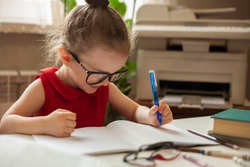 
Left-handed. International left-handed day. Girl in glasses for sight. A girl writes in a notebook with her left hand. Education and science. Preschool education.