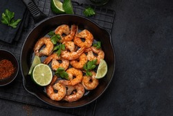 spicy roasted shrimps in cast iron pan , black background, top view, copy space