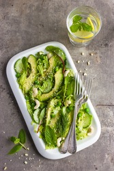 Salad with savoy cabbage, avocado, cucumber and nuts on white plate, top view