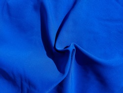 popular Cyan blue fabric waves background. Bright sapphire cloth texture. Swirl waves on smooth textile saturated blue color.