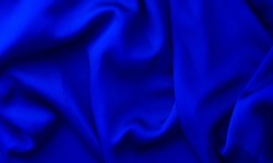 Cyan blue fabric waves background. Bright sapphire cloth texture. Swirl waves on smooth textile saturated blue color. Ukrainian color symbol of freedom.