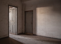 Sunlight is falling through an empty room of an old, deserted building.