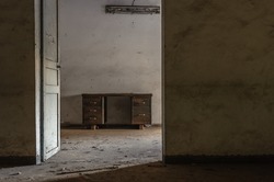 Desk in an empty room in an abandoned office building, looking through a doorway.