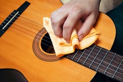 Musical instrument care. Guitar cleaning. Man cleaning a guitar