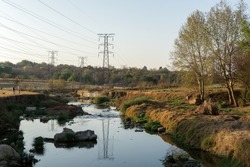 Multiple Power Transmission Towers crossing a peaceful river in an open urban area - strong contrast