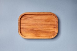 Empty wooden tray on textured dark blue table. Rectangular wooden dish top view. Kitchen minimal flat lay