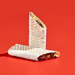 Shawarma wrap with beef on color background with hard shadow. Beef shawarma sandwich in abstract style. Simple fast food in minimal concept. Lebanese food. Shadow sunlight.