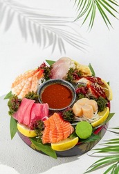 Sashimi set from raw seafood: salmon, tuna, eel, perch, shrimps, sea scallop. Traditional japanesse dish - sashimi on white background. Fresh delicacy on ice with lemon, ginger and sauce