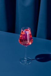 Elegant cocktail with red vermouth on blue background with shadow. Vermouth cocktail on coloured background in trendy style. Contemporary concept with alcohol beverage. Bartender cocktail