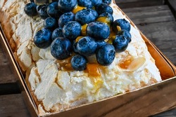 Anna Pavlova's dessert with blueberries. Fresh meringue roll on a wooden table.