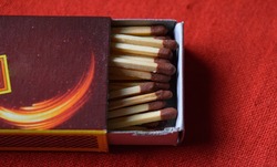 Closeup of wooden match sticks inside a matchbox isolated on a red background (Top View)