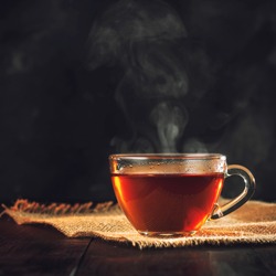 A Cup of freshly brewed black tea,escaping steam,warm soft light, darker background.