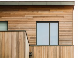 Modern wooden facade with flat roof and aluminium window