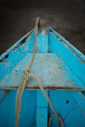 Detail of a small old wooden boat with blue color and dew interior view front part
