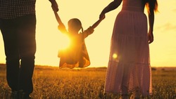 mother father kid daughter summer park sunset. child kid holding parents hands. happy family holiday. runs jumps up kid child. mom dad baby girl walk along green meadow park. family vacation innature