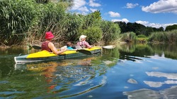family kayak on the river, which reflects the blue sky with clouds