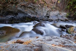 Pure water stream with smooth flow over rocky mountain terrain in the Kakopetria forest in Troodos, Cyprus. Slow exposure creating sooth flow impression.