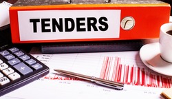 TENDERS is written on a red document folder near a pen, calculator, coffee cup and graphs.