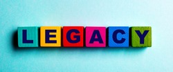 The word LEGACY is written on multicolored bright wooden cubes on a light blue background