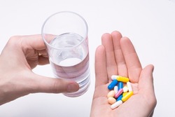 On a light background, male hands with pills and a glass of water. Medical concept