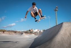 Young skateboarder man does a trick called `boneless` in a ramp of a skate park.