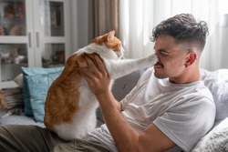 young man and brown and white cat play together in the living room